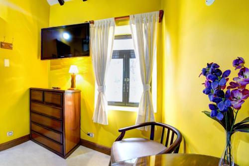 a yellow room with a table and a vase of purple flowers at La Posada De Los Cóndores in Chaclacayo