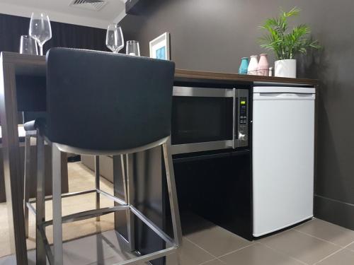 a kitchen with a bar with a chair and a refrigerator at Hotel Grand Chancellor Townsville in Townsville