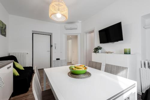 ミラノにあるStayEasy Filzi11 - 3 Bedrooms, 2 baths - Central Stationの白いキッチン(フルーツの盛り合わせ付きのテーブル付)