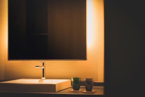 a bathroom with a sink and two green glasses at Hakone Kowakien Tenyu in Hakone