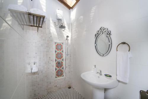 a white bathroom with a sink and a mirror at Jawi Peranakan Mansion in George Town