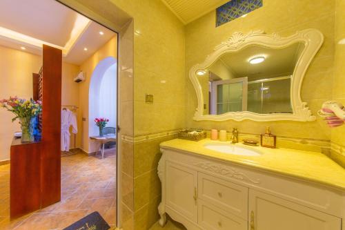 ein Bad mit einem Waschbecken und einem Spiegel in der Unterkunft Mengyuanju Boutique Inn in Dali