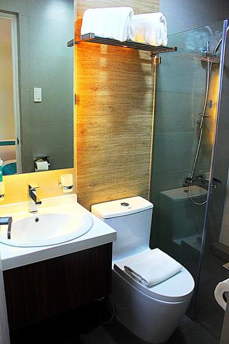 a bathroom with a toilet and a sink and a mirror at Hotel Estrella in Tacloban