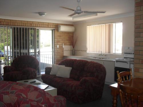 a living room with two couches and a kitchen at Beachlander Self-Contained Holiday Apartments in Coffs Harbour