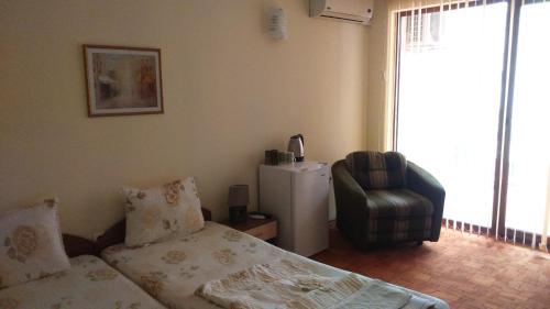 a bedroom with a bed and a chair and a window at Guest House Pri Valyo in Primorsko