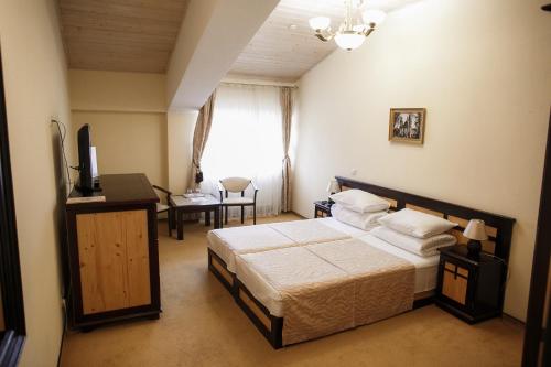 a bedroom with a bed and a desk and a television at Georg Palace Hotel in Chernivtsi