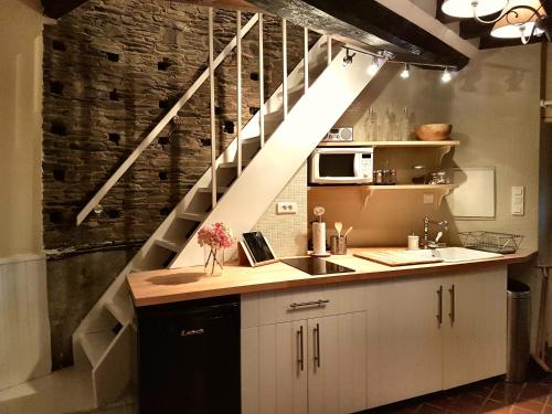 a kitchen with a counter with a sink and a staircase at La Coulombe Manoir De Hérouville in Litteau