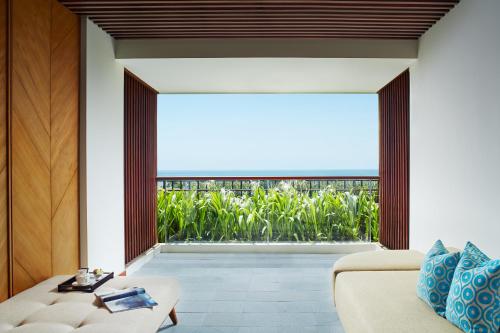 an open living room with a large window and a couch at MERUSAKA Nusa Dua in Nusa Dua