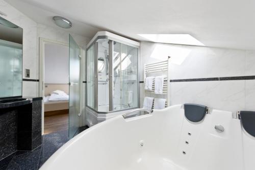 a bathroom with a white tub and a sink at Boutique-garni Hotel Papillon in Kempen