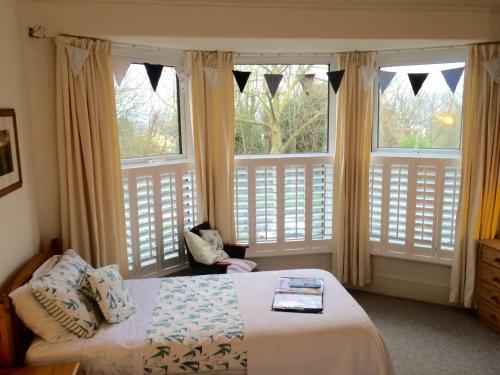 a bedroom with a bed and two large windows at Trelawney Guest House in Falmouth