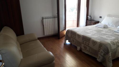 a bedroom with a bed and a couch and a window at RELAX locazione turistica in Ceregnano