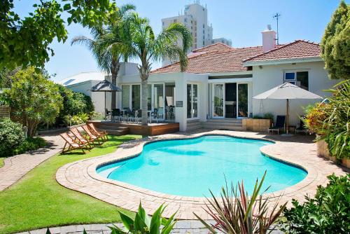 
a house with a pool and lawn chairs at First Avenue Guesthouse in Port Elizabeth
