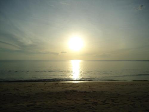 a sun setting over the ocean on a beach at Sea Breeze House, Naiplao Beach in Khanom