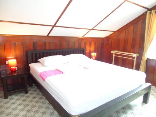 a bedroom with a white bed with wooden walls at Sea Breeze House, Naiplao Beach in Khanom