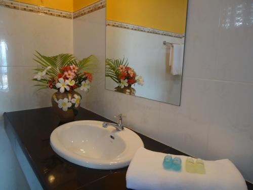 a bathroom with a sink and a mirror and flowers at Sea Breeze House, Naiplao Beach in Khanom