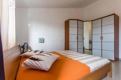 sypialnia z pomarańczowym łóżkiem z poduszkami w obiekcie Apartments Gloria w mieście Ližnjan