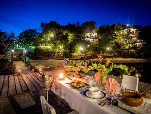 a table with food and candles on a deck at night at La Estancia Busuanga in Busuanga