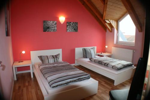 2 Betten in einem Zimmer mit roten Wänden in der Unterkunft Ferienwohnung Weinberg in Gründau