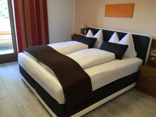 a bedroom with a large bed with black and white pillows at Biogasthaus Plonerhof in Bressanone