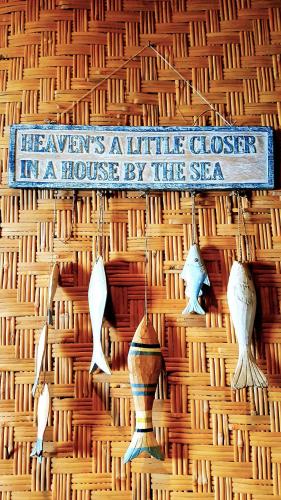 a sign on a wall with a house by the sea at Palmyra Indah Bungalows in Sekotong