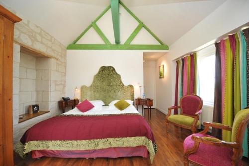 a bedroom with a large bed and two chairs at Logis Demeure de la Vignole in Turquant