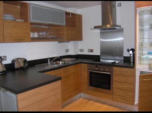 a kitchen with wooden cabinets and a black counter top at Leeds City Centre Apartments in Leeds