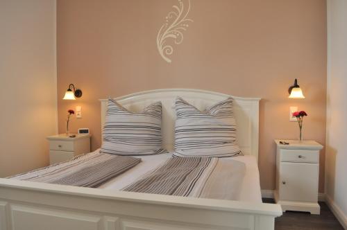 een wit bed met witte kussens en 2 nachtkastjes bij Ferienwohnungen Gehlberg in Gehlberg
