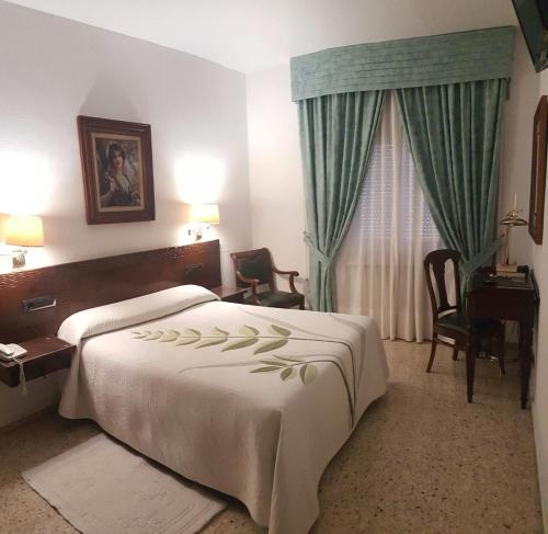 a hotel room with a bed and a desk and a window at Hotel Nico in Medinaceli