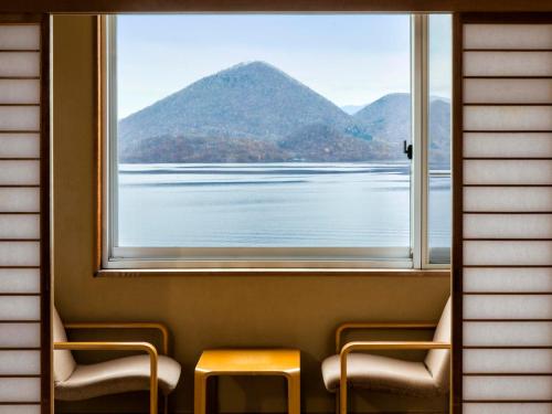 two chairs and a table in front of a window at Toya Kohan Tei in Lake Toya