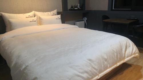 uma grande cama branca com lençóis e almofadas brancos em Hotel Prince em Busan