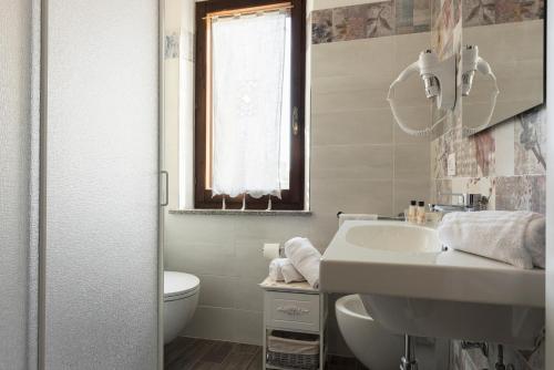 a white bathroom with a sink and a toilet at Il Pozzetto in Ravigliano