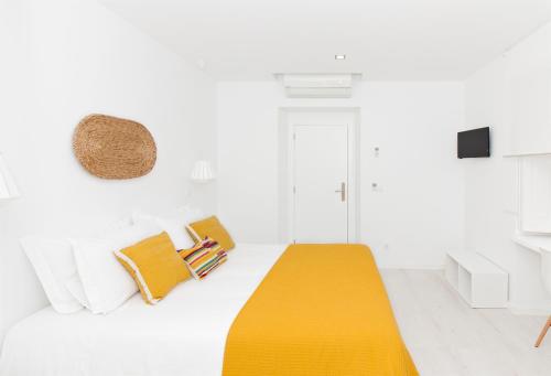 a white room with a bed with a yellow blanket at Villa Maça House in Sintra