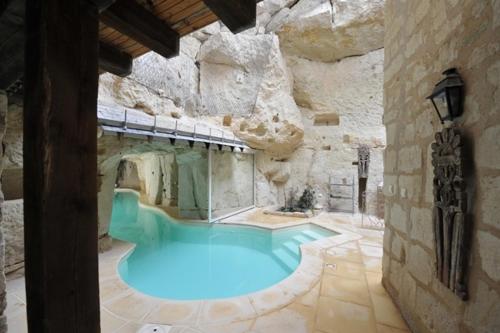 a large swimming pool in a stone building at Logis Demeure de la Vignole in Turquant