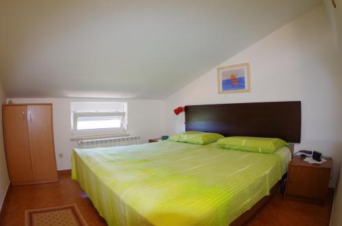 een slaapkamer met een groot bed met een groene sprei bij Apartments Kreso in Fažana