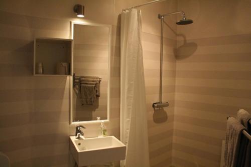 a bathroom with a sink and a shower with a mirror at Strandhotellet in Öregrund