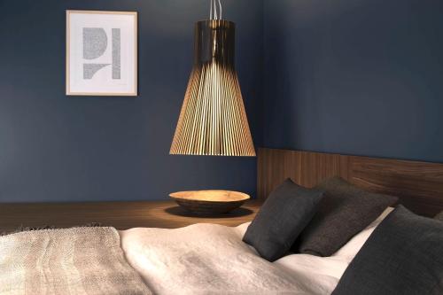 a bed with a lamp on top of it next to a wall at La Remise Suites in Amsterdam