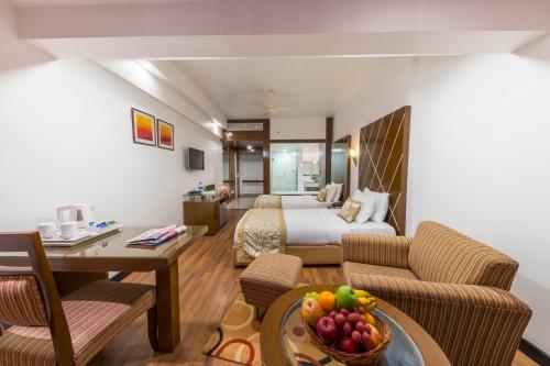 a hotel room with a bed and a table with a bowl of fruit at Hotel Hindusthan International, Bhubaneswar in Bhubaneshwar