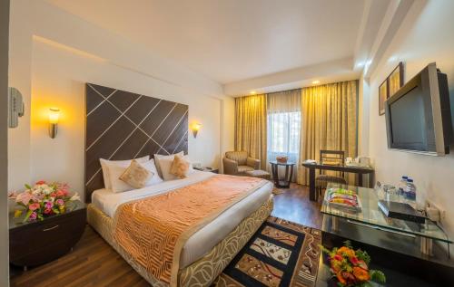 a hotel room with a bed and a television at Hotel Hindusthan International, Bhubaneswar in Bhubaneshwar