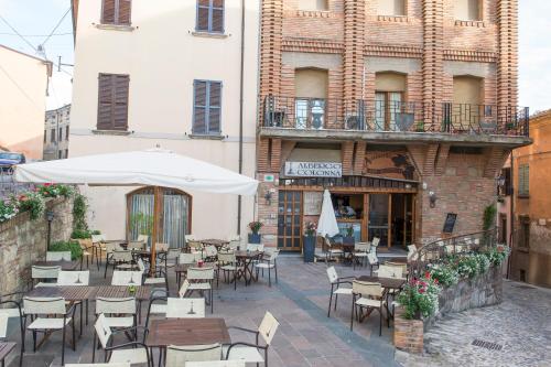 an outdoor cafe with tables and chairs and an umbrella at Albergo Colonna in Bertinoro