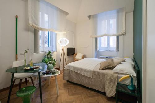 - une chambre avec un lit, une table et deux fenêtres dans l'établissement Limoncello Rooms, à Salerne