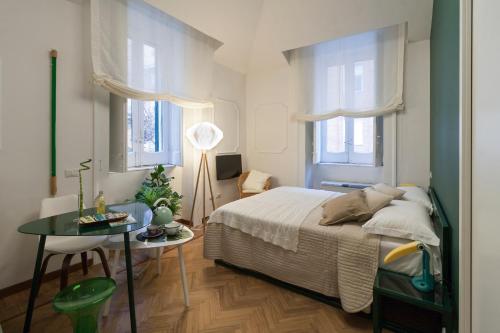 Un dormitorio con una cama y una mesa y dos ventanas. en Limoncello Rooms, en Salerno