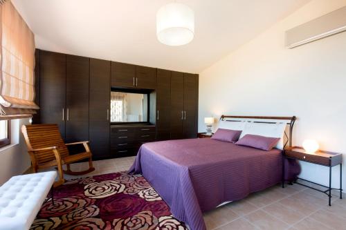 a bedroom with a bed and a chair and a table at Villa Leyland in Faliraki