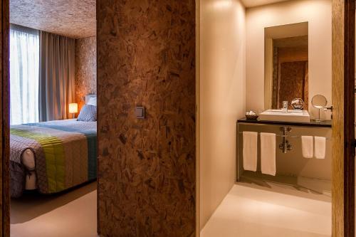 a hotel room with a bed and a bathroom at Paraíso Villas & Spa in Guimarães