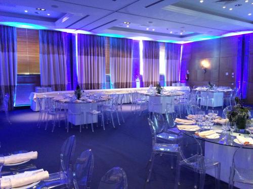 a banquet hall with white tables and chairs and purple lighting at Grande Real Villa Itália Hotel & Spa in Cascais