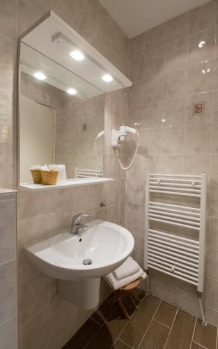 a bathroom with a sink and a mirror at LOGIS Hôtel & Restaurant - Au Bord du Lac in Saint-Rémy-lès-Chevreuse