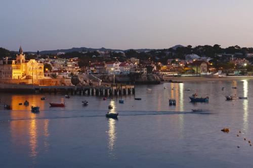 a group of boats in the water with a city at Grande Real Villa Itália Hotel & Spa in Cascais