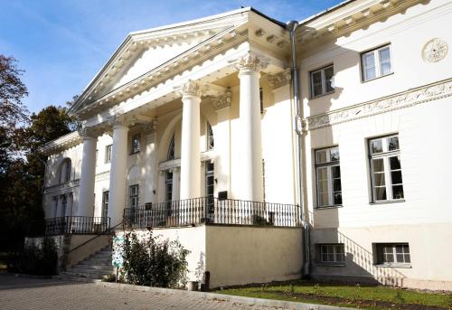 a large white building with columns at Saku Manor & Beerspa in Saku