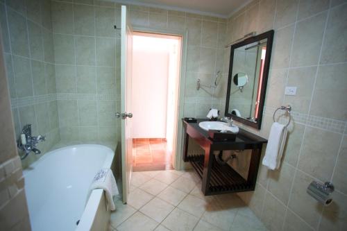 La salle de bains est pourvue d'une baignoire, d'un lavabo et d'une baignoire. dans l'établissement Haile Resort Hawassa, à Awasa