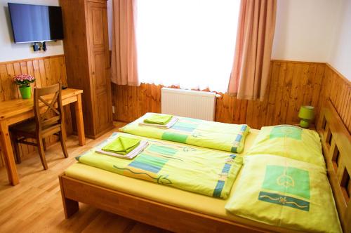 a bedroom with a bed with yellow sheets and a table at Vila Pod Bránou in Poprad