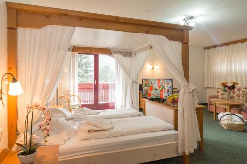 a bedroom with a canopy bed with a window at Hotel Hellweger in Campo Tures